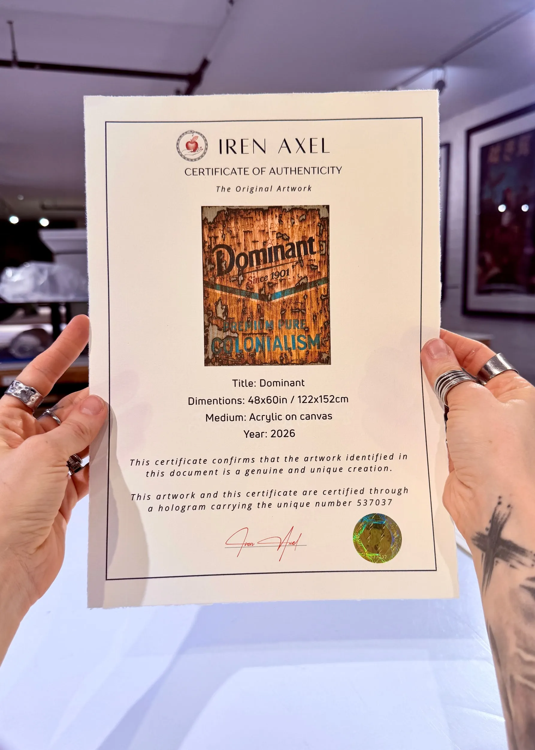 The signed certificate of authenticity for Dominant, hologram number 537037, held up in the gallery