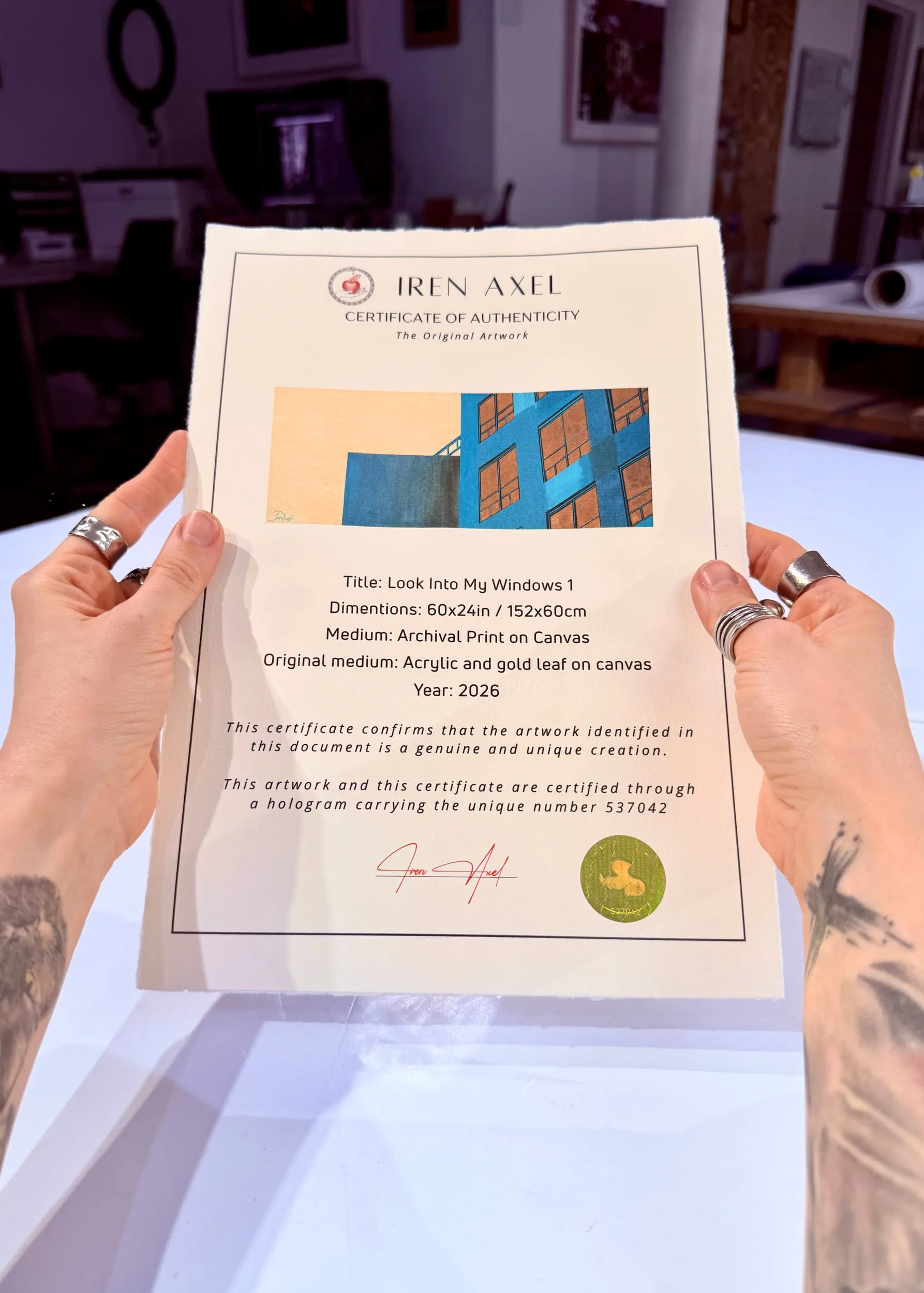The signed certificate of authenticity for Look Into My Windows 1, hologram number 537042, held up in the gallery