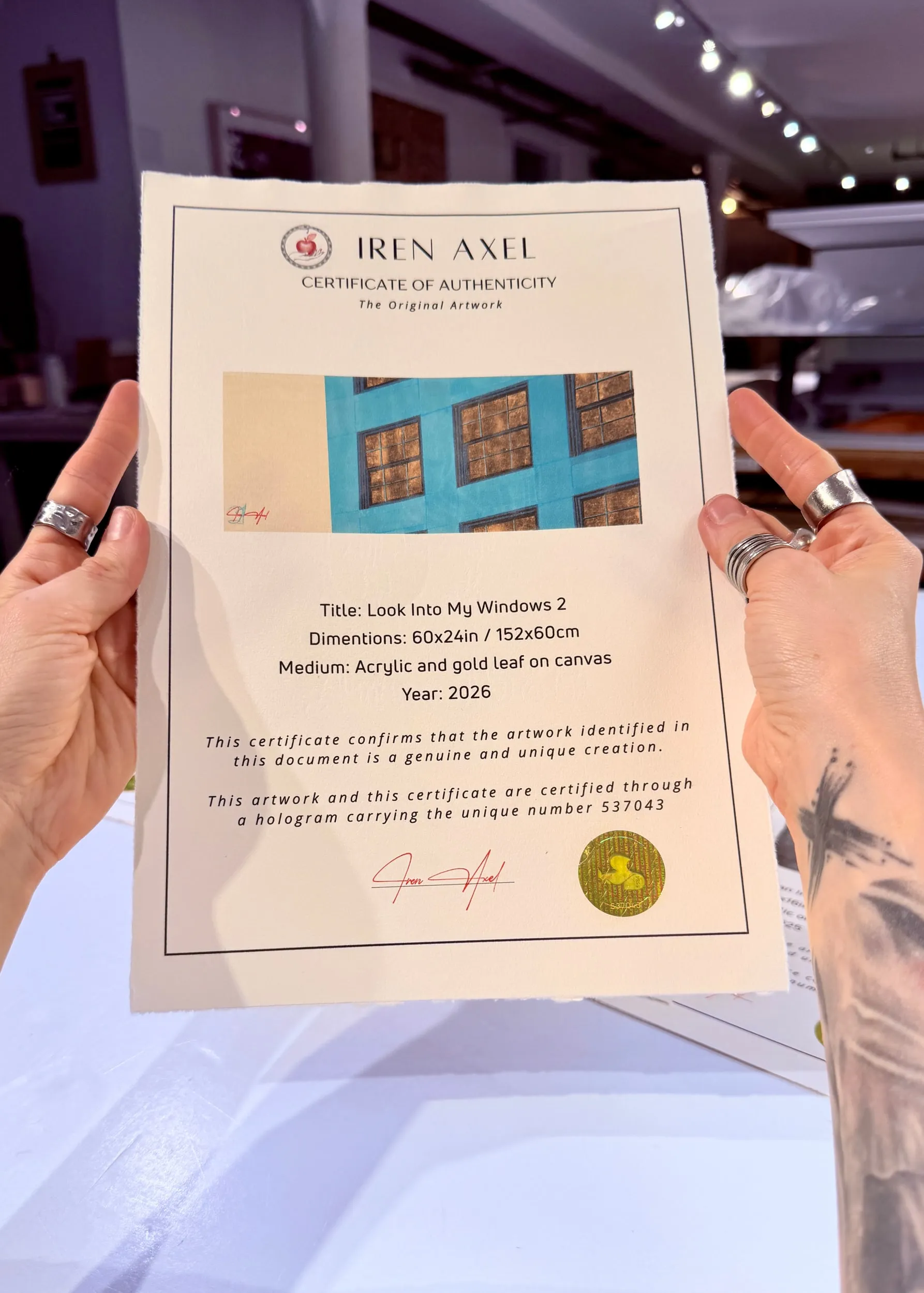 The signed certificate of authenticity for Look Into My Windows 2, hologram number 537043, held up in the gallery