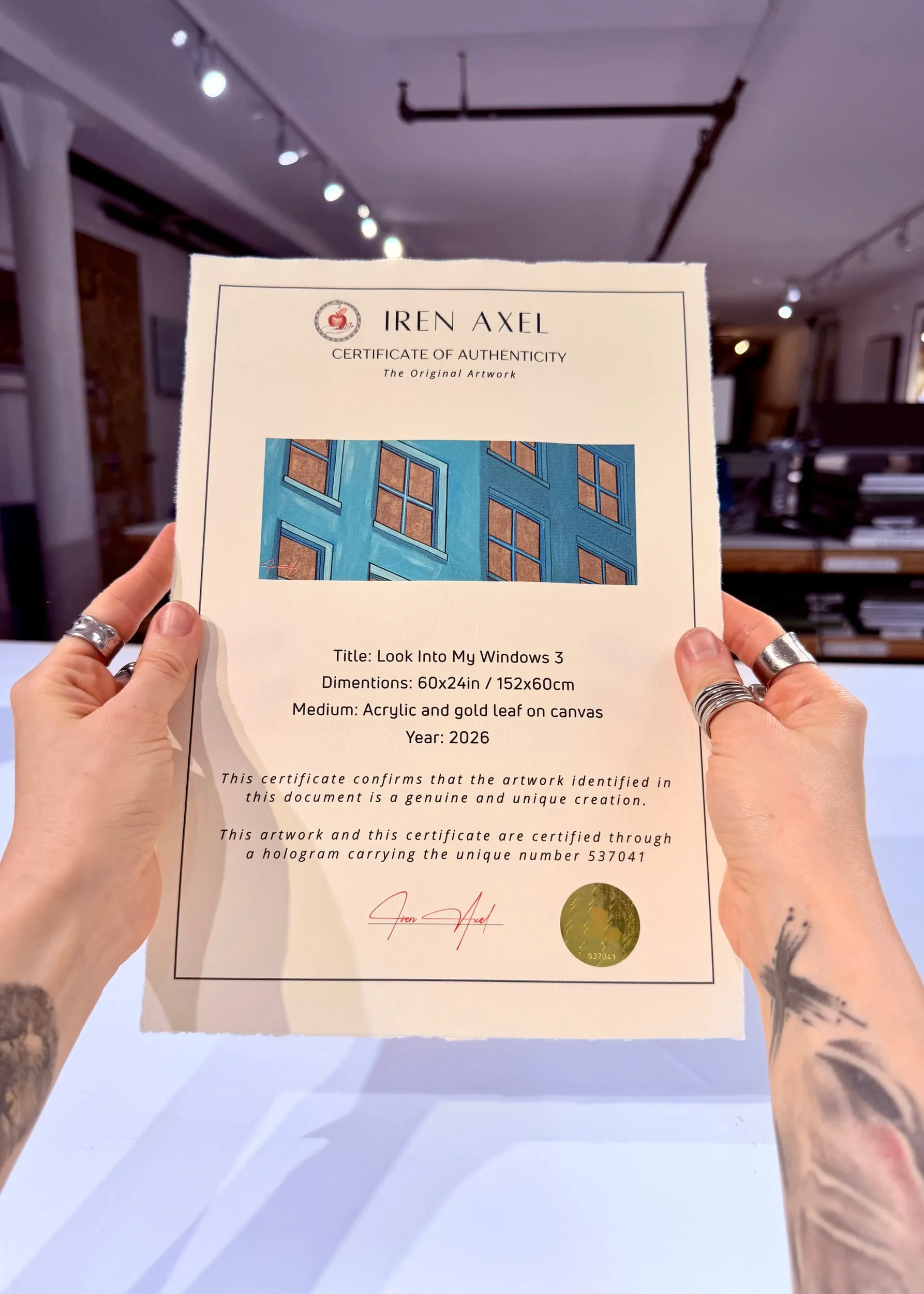 The signed certificate of authenticity for Look Into My Windows 3, hologram number 537041, held up in the gallery